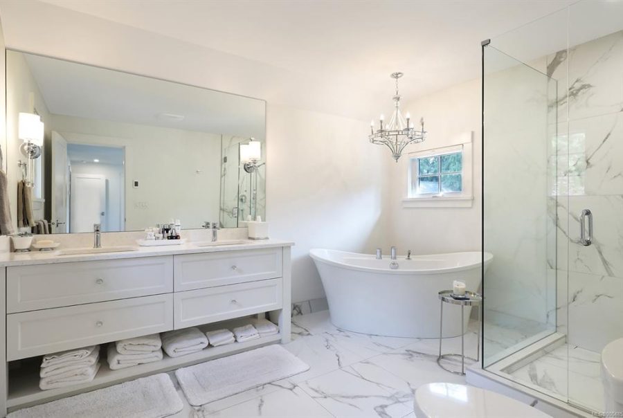 Bright bathroom with freestanding tub, chandelier, and glass walk‑in shower