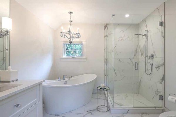 Bright bathroom with freestanding tub, chandelier, and glass walk‑in shower
