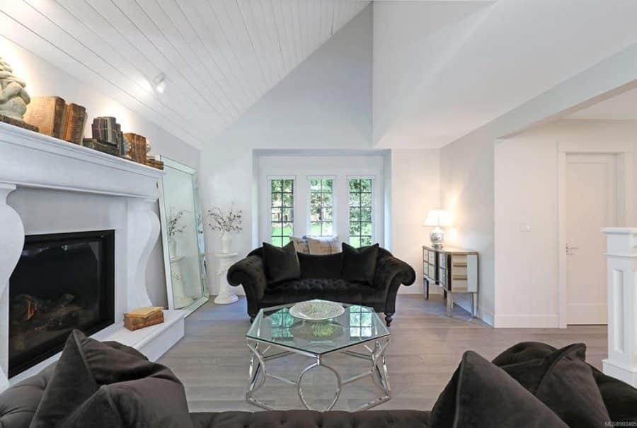 Elegant living room with fireplace, black velvet sofas, and light wood flooring in Vancouver Island beach home