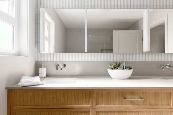 Modern bathroom renovation with dual-sink vanity, wall-mounted faucets, and custom cabinetry.