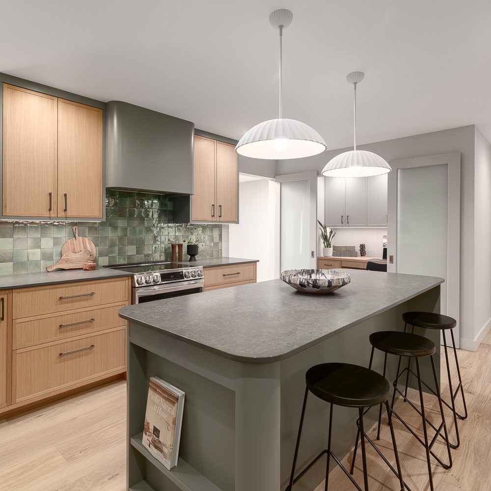 Kitchen with green tile backsplash, pendant lights, and view into home office through frosted glass doors