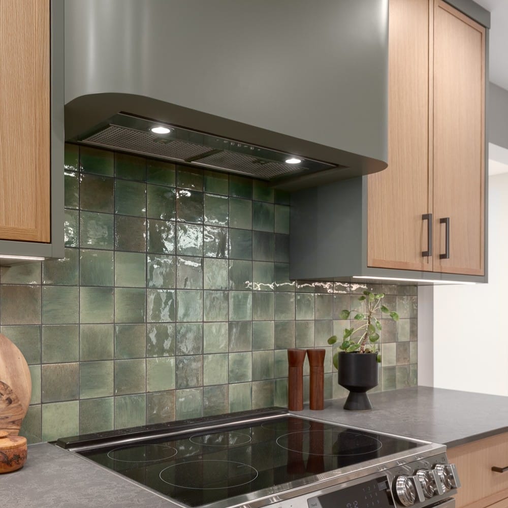 Bright, modern kitchen with full-height wood cabinetry, dark island, and pendant lighting.