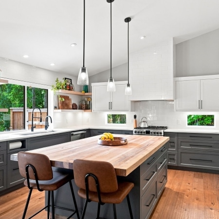 Modern West Coast kitchen with custom cabinetry, wood‑accented island, and pendant lighting, built by Pickard Construction in the Parksville–Qualicum Beach area.