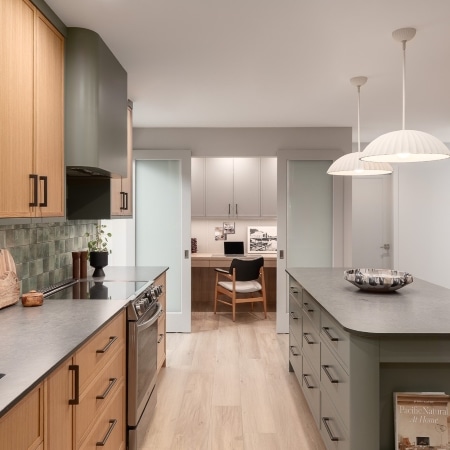 Modern kitchen with green cabinetry, wood accents, and a large island, completed under Pickard Construction as the general contractor in the Parksville–Qualicum Beach area.