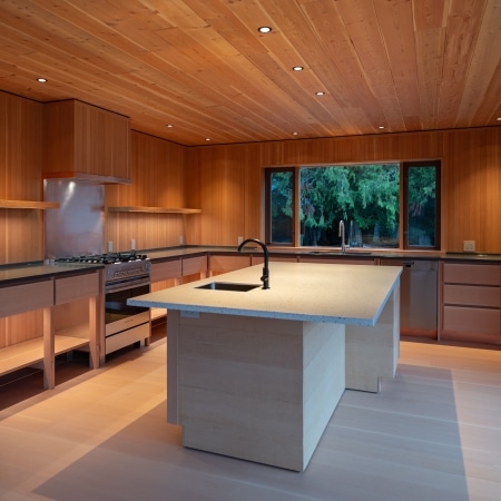 Modern wood‑ceiling kitchen with custom cabinetry, large island, and minimalist West Coast design built by Pickard Construction in the Parksville–Qualicum Beach area.